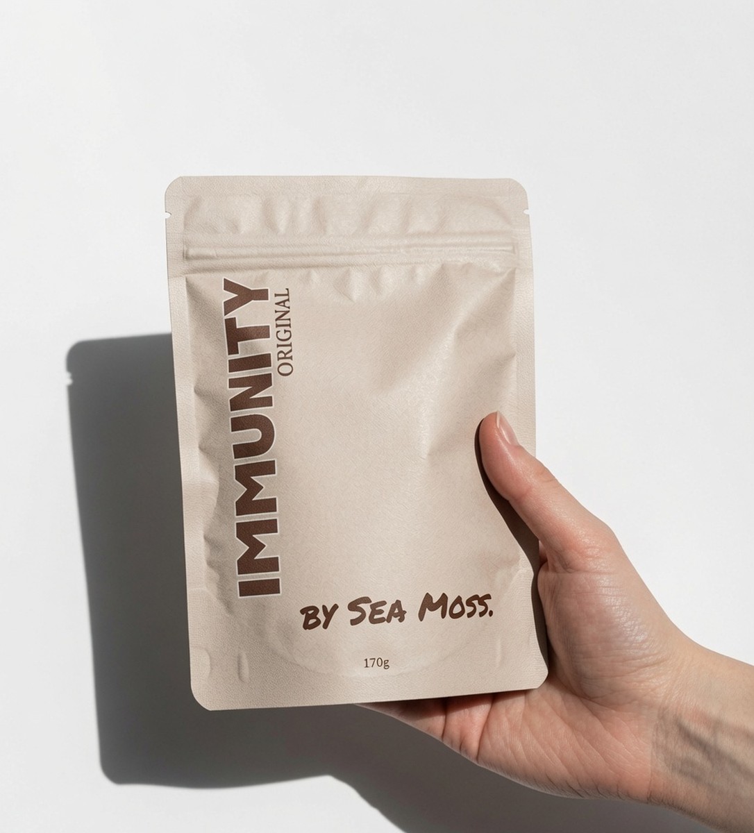 A hand holding a 170g pouch of By Sea Moss. Immunity Original sea moss powder